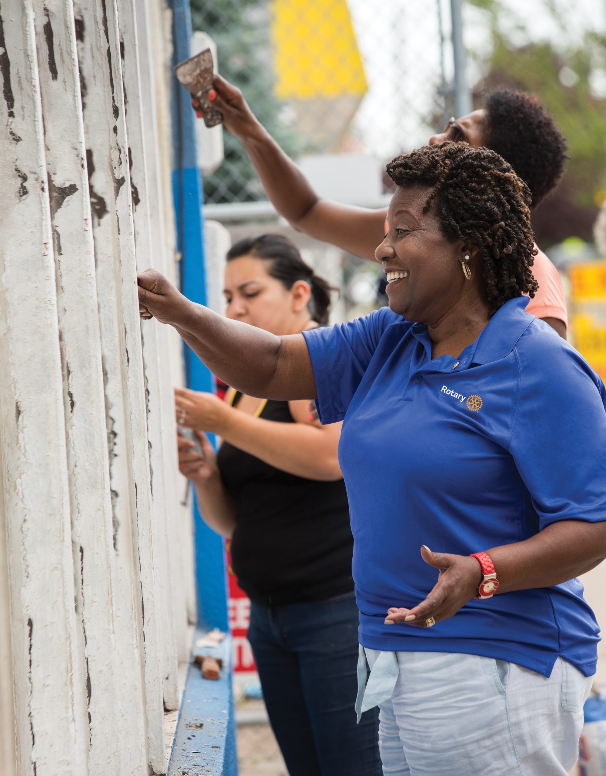 Mary Ferris (right), of the Rotary Club of Detroit, scrapes paint from the facade of Irma Fuentes' hardware store in Detroit, Michigan, USA, 25 July 2014.